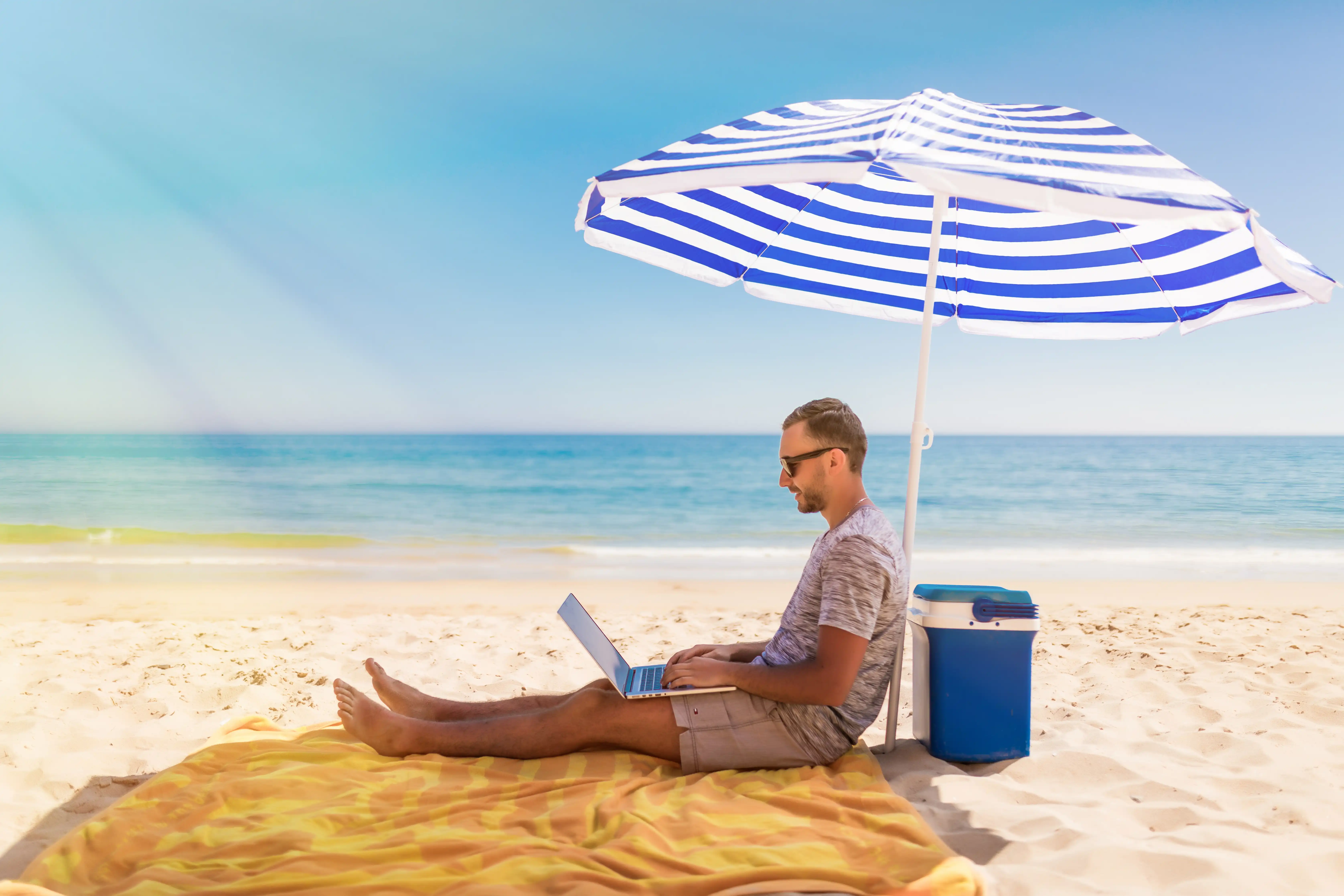 Remote werken in Marokko - Professional werkt op strand met laptop - Hybride vacatures voor Nederlandstaligen